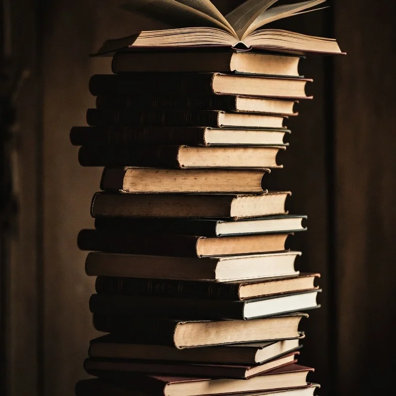 Pilha alta e desorganizada de livros antigos.